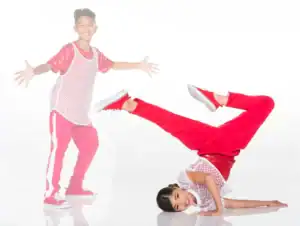 Two children in red outfits dancing against white background