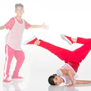 Two children in red outfits dancing against white background