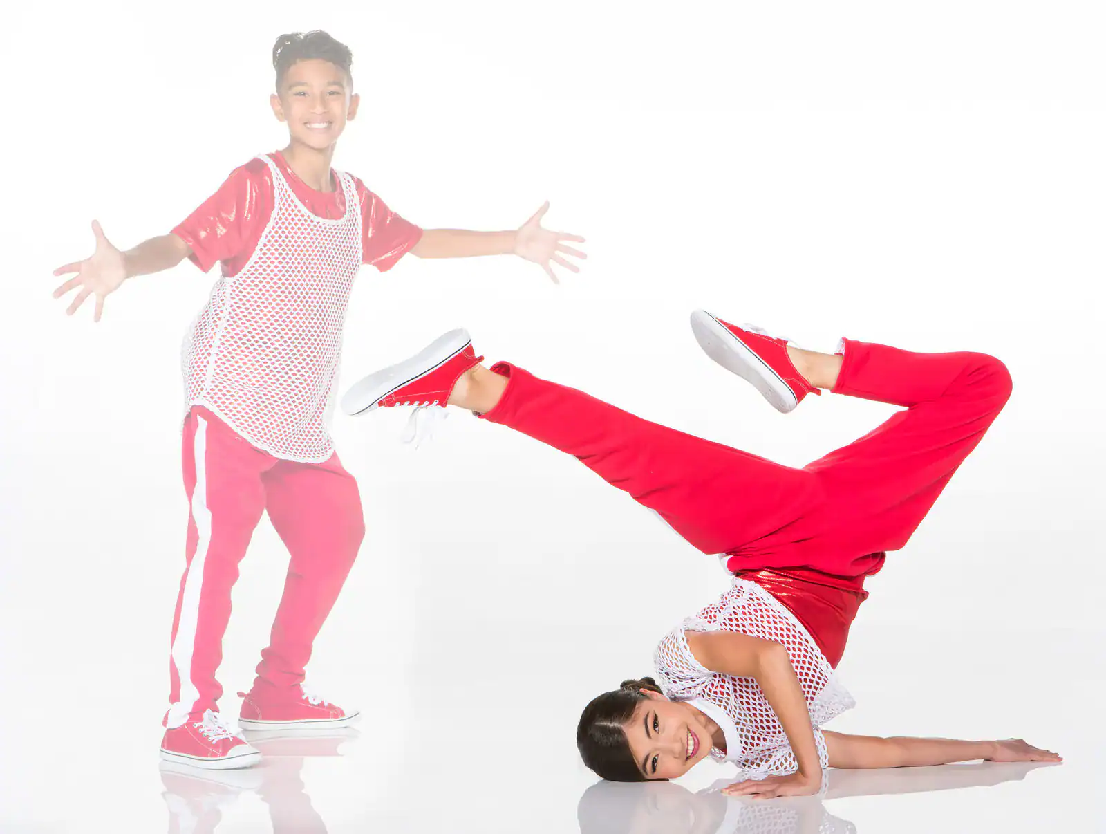 Two children in red outfits dancing against white background