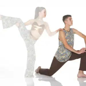 Two dancers pose in colorful patterned outfits on white background.