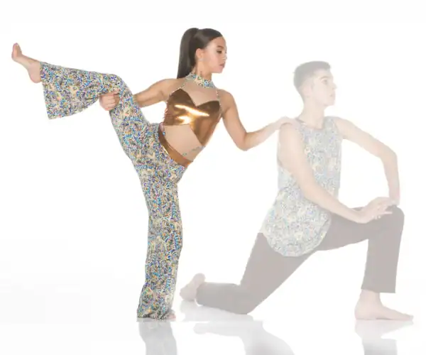 Dancer performing high leg stretch beside kneeling partner