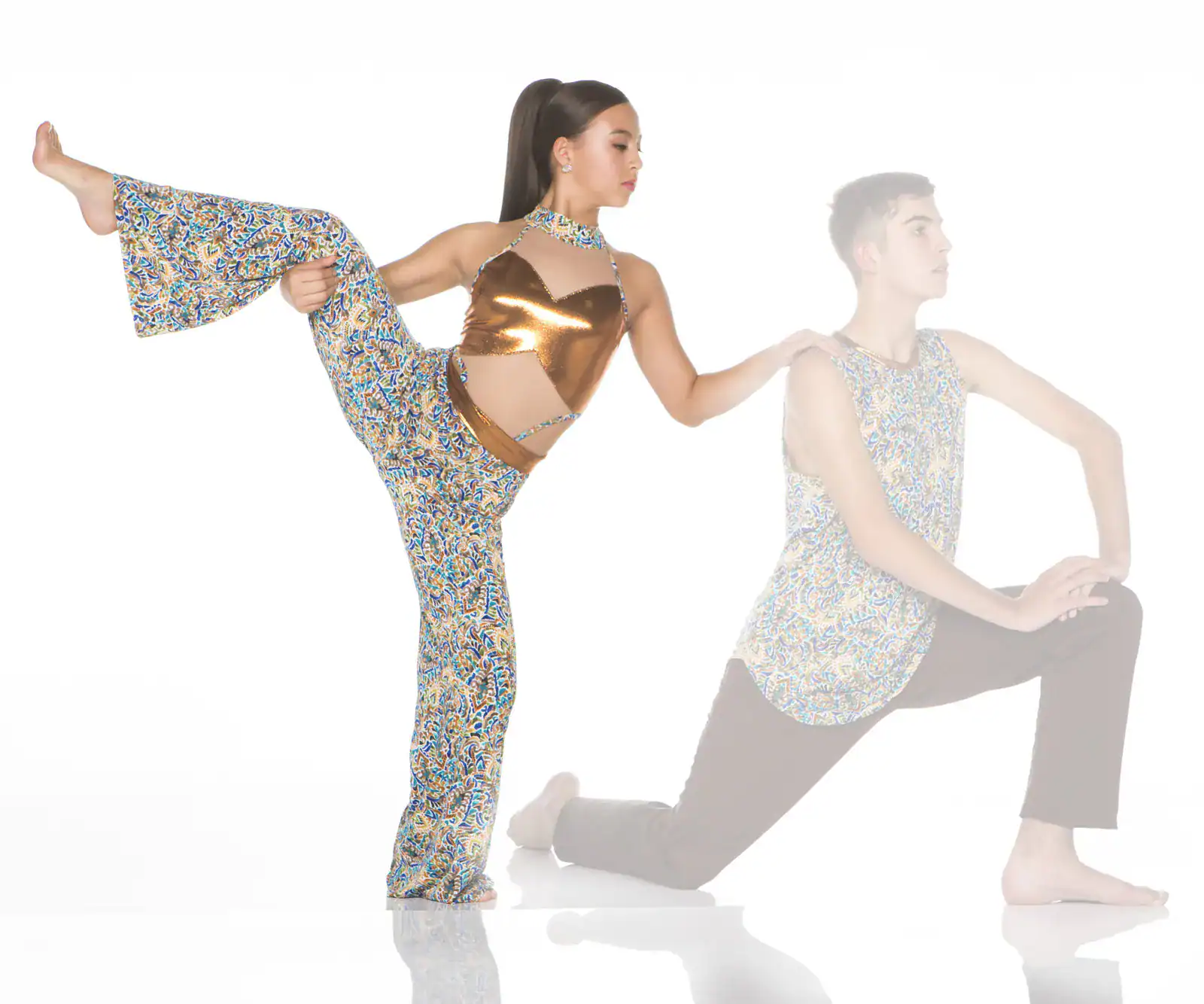 Dancer performing high leg stretch beside kneeling partner