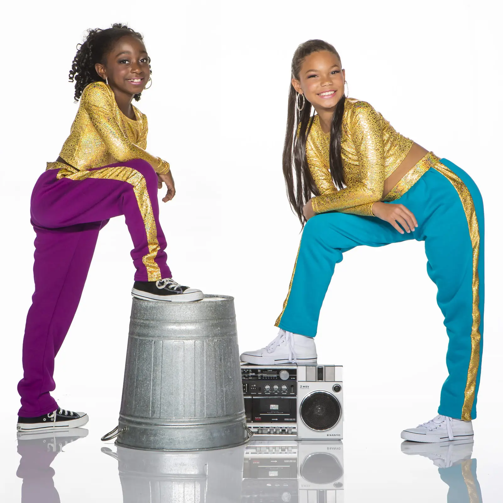 Two girls in glittery gold outfits pose with boombox.